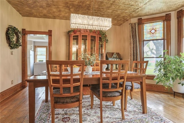 dining room with hardwood / wood-style flooring, a chandelier, and baseboards