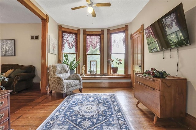 living area featuring wood finished floors, a ceiling fan, and a textured ceiling
