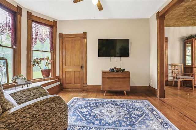 living room featuring wood finished floors, a ceiling fan, and baseboards