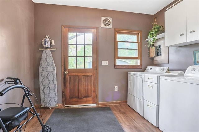 laundry area with washing machine and clothes dryer, cabinet space, light wood-style floors, and baseboards
