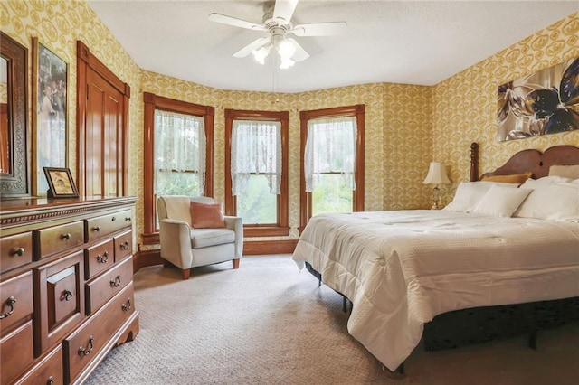 bedroom with wallpapered walls, light colored carpet, and ceiling fan