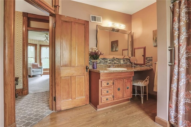 full bathroom featuring wood finished floors, backsplash, and vanity