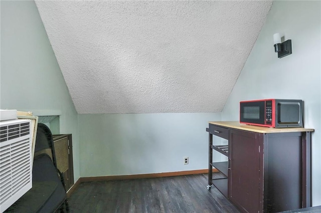 office with a textured ceiling, dark wood-style floors, baseboards, and vaulted ceiling