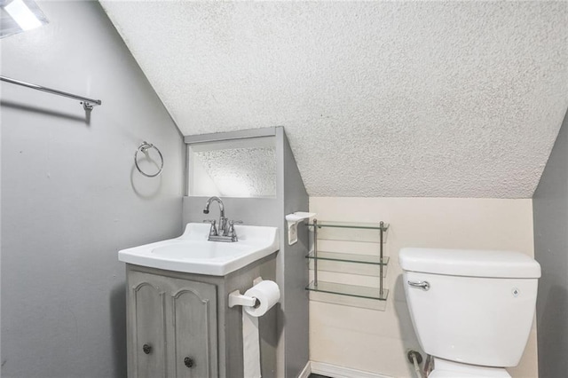 bathroom featuring vaulted ceiling, a textured ceiling, toilet, vanity, and baseboards