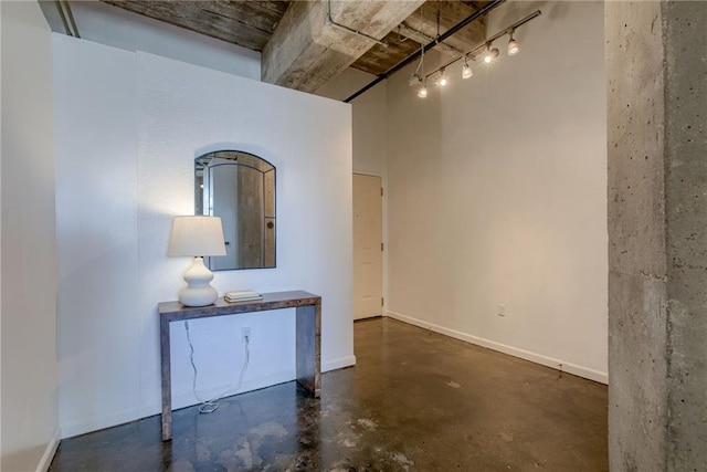 spare room with finished concrete flooring, baseboards, and rail lighting