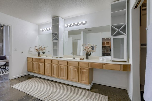 bathroom with baseboards, double vanity, a textured ceiling, and concrete floors