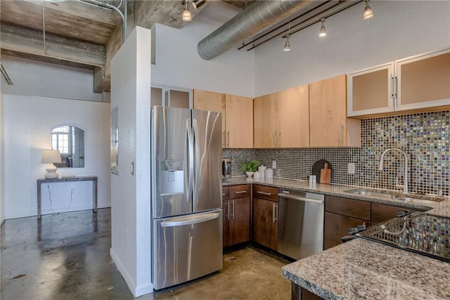 kitchen featuring appliances with stainless steel finishes, concrete flooring, a sink, and tasteful backsplash
