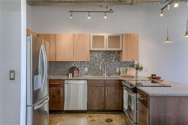 kitchen featuring stainless steel appliances, a sink, rail lighting, and tasteful backsplash