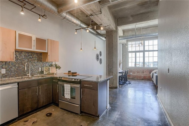 kitchen with stainless steel appliances, a sink, concrete flooring, backsplash, and a peninsula
