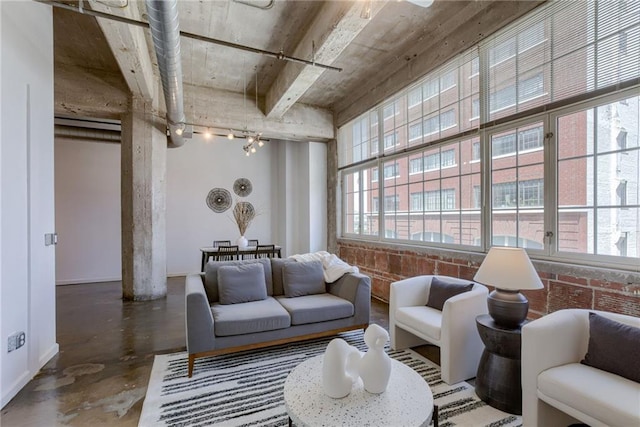 living area featuring concrete flooring, track lighting, and baseboards