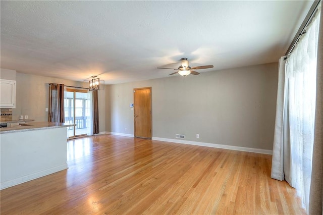 11205 E 49th St, Kansas City, MO 64133 - unfurnished living room featuring a ceiling fan, a chandelier, light wood-style floors, and baseboards