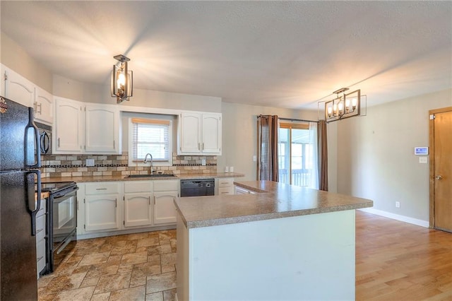 11205 E 49th St, Kansas City, MO 64133 - kitchen featuring a sink, black appliances, white cabinets, decorative backsplash, and a center island