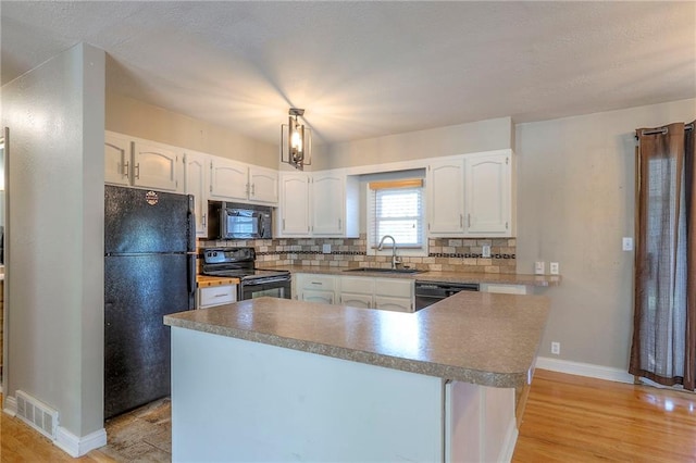 11205 E 49th St, Kansas City, MO 64133 - kitchen featuring black appliances, a sink, light wood finished floors, white cabinetry, and tasteful backsplash