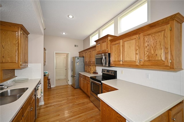 3112 NW 86th St, Kansas City, MO 64154 - kitchen with stainless steel appliances, a sink, brown cabinets, tasteful backsplash, and light wood finished floors