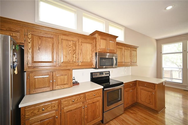 3112 NW 86th St, Kansas City, MO 64154 - kitchen with stainless steel appliances, a peninsula, brown cabinets, and light countertops