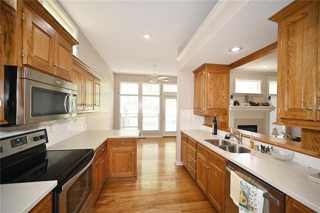3112 NW 86th St, Kansas City, MO 64154 - kitchen with stainless steel appliances, a sink, light wood-type flooring, ceiling fan, and a fireplace