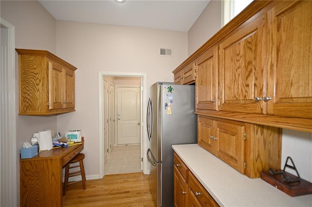 3112 NW 86th St, Kansas City, MO 64154 - kitchen with freestanding refrigerator, brown cabinets, light wood-style flooring, light countertops, and baseboards