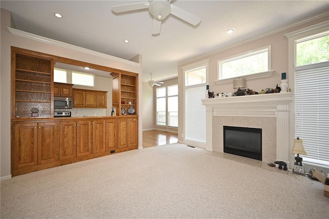 3112 NW 86th St, Kansas City, MO 64154 - living room with a ceiling fan, light colored carpet, ornamental molding, a tiled fireplace, and baseboards