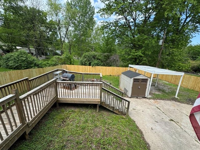 1606 N Ponca Dr, Independence, MO 64058 - wooden deck featuring a shed, a fenced backyard, an outdoor structure, and view of scattered trees