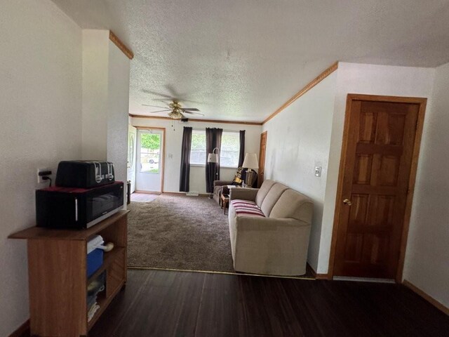 1606 N Ponca Dr, Independence, MO 64058 - living area with dark wood-type flooring, a textured ceiling, a ceiling fan, and baseboards