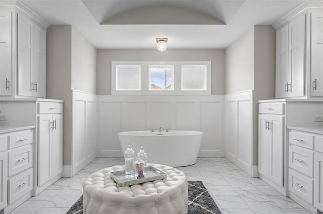 15624 Delmar St, Overland Park, KS 66224 - bathroom with marble look tiles, a decorative wall, a freestanding tub, wainscoting, and vanity