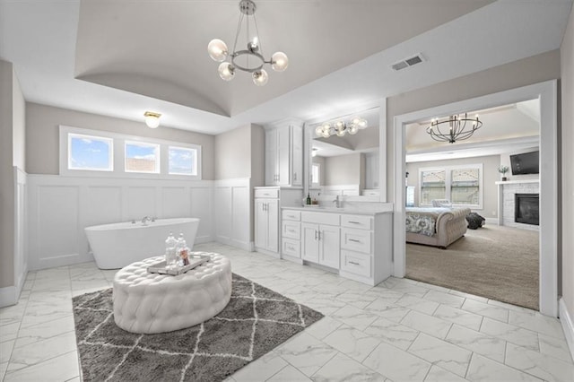 15624 Delmar St, Overland Park, KS 66224 - full bath featuring marble finish floors, a chandelier, a soaking tub, vanity, and a glass covered fireplace