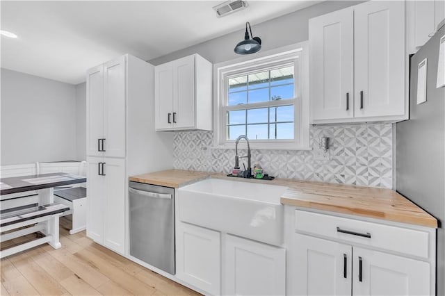 252 SE 23rd Hwy, Knob Noster, MO 65336 - kitchen featuring stainless steel dishwasher, butcher block countertops, light wood-style flooring, white cabinetry, and tasteful backsplash