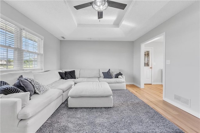 252 SE 23rd Hwy, Knob Noster, MO 65336 - living room featuring a tray ceiling, wood finished floors, a ceiling fan, baseboards, and a textured ceiling