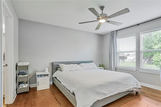 bedroom featuring multiple windows, wood finished floors, and baseboards