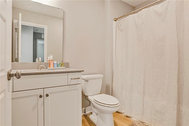 bathroom with toilet, wood finished floors, vanity, and a shower with curtain