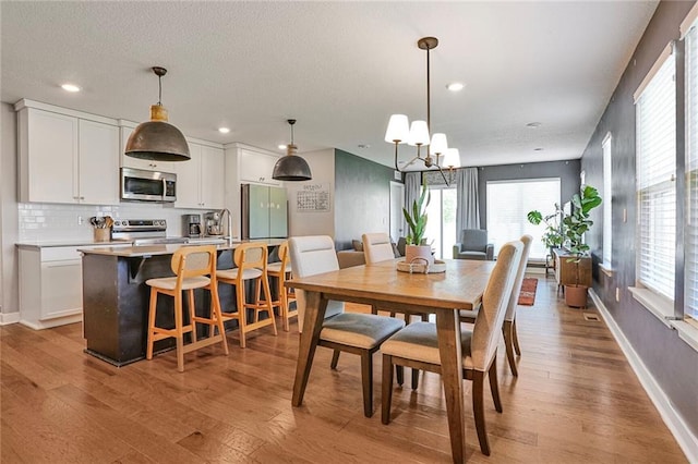 dining space featuring a chandelier, light wood-style flooring, recessed lighting, and baseboards