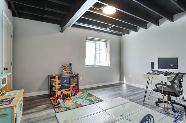 game room featuring wood finished floors, a desk, beam ceiling, and baseboards