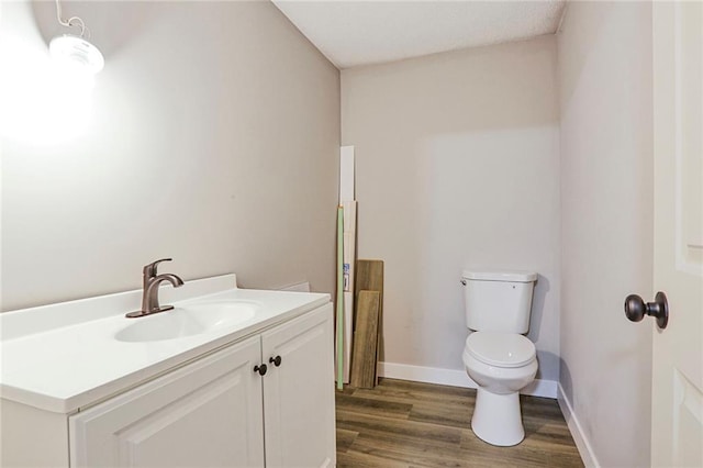 bathroom featuring toilet, wood finished floors, vanity, and baseboards