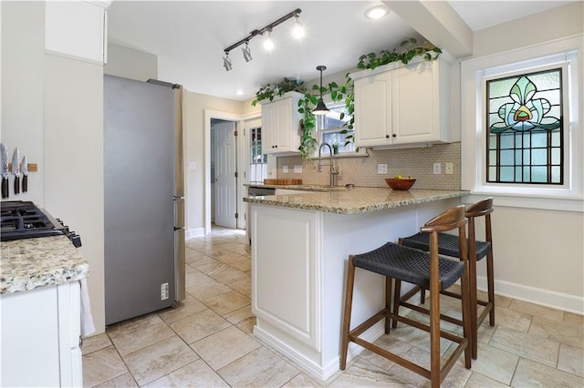 23 W Winthrope Rd, Kansas City, MO 64113 - kitchen with freestanding refrigerator, a sink, a peninsula, tasteful backsplash, and healthy amount of natural light
