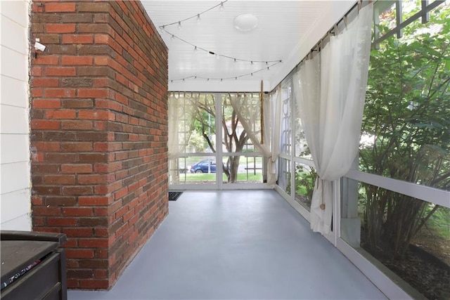 23 W Winthrope Rd, Kansas City, MO 64113 - unfurnished sunroom with concrete floors, a wood stove, and brick wall
