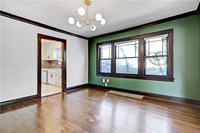 2414 N 12th St, Kansas City, KS 66104 - empty room with ornamental molding, a chandelier, wood finished floors, baseboards, and a sink