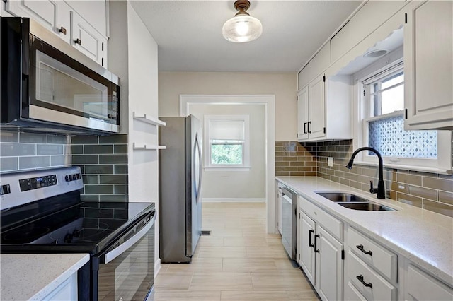 2414 N 12th St, Kansas City, KS 66104 - kitchen with stainless steel appliances, a sink, white cabinets, and decorative backsplash