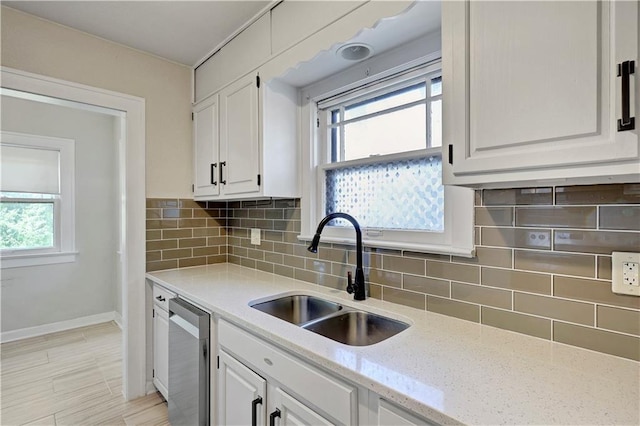 2414 N 12th St, Kansas City, KS 66104 - kitchen with a sink, stainless steel dishwasher, white cabinetry, baseboards, and tasteful backsplash