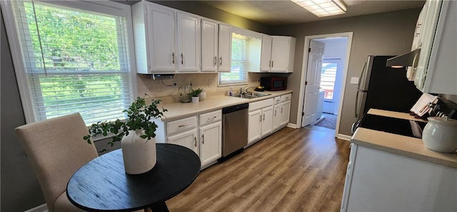 7934 Hemlock St, Overland Park, KS 66204 - kitchen with stainless steel dishwasher, a sink, white cabinetry, light countertops, and wood finished floors