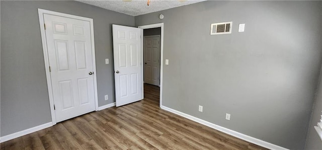 7934 Hemlock St, Overland Park, KS 66204 - unfurnished bedroom featuring baseboards, a textured ceiling, and wood finished floors
