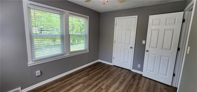 7934 Hemlock St, Overland Park, KS 66204 - unfurnished bedroom featuring multiple windows, dark wood-style flooring, baseboards, a textured ceiling, and ceiling fan