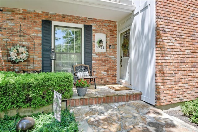 doorway to property with brick siding and covered porch