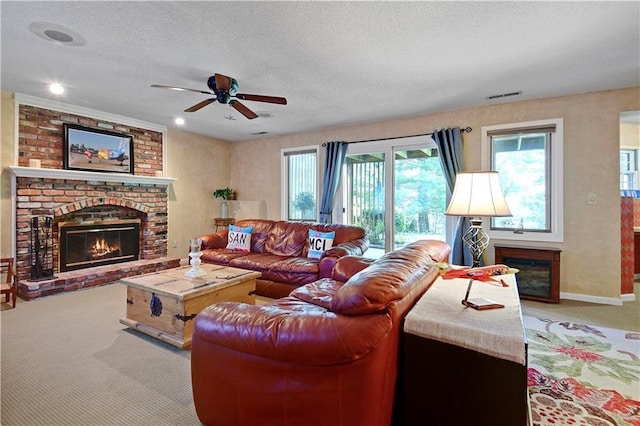 living room with a brick fireplace, carpet, a ceiling fan, a textured ceiling, and baseboards