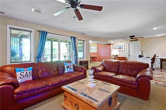 living room featuring ceiling fan, carpet floors, and a textured ceiling