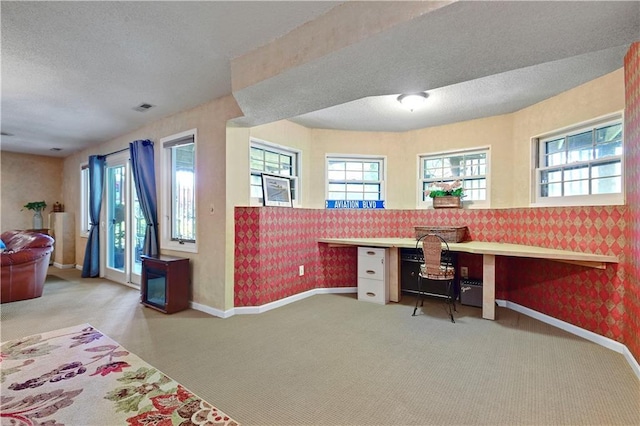 carpeted office space with plenty of natural light, wallpapered walls, baseboards, a textured ceiling, and built in study area