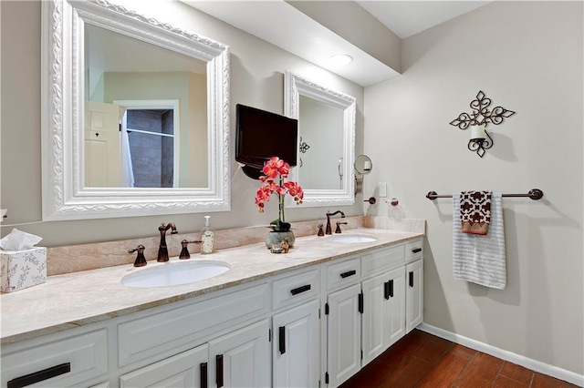 full bathroom with double vanity, baseboards, wood finished floors, and a shower