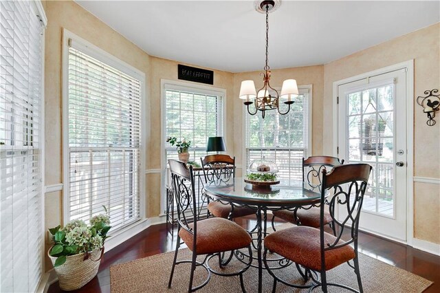 dining space with dark wood-type flooring, healthy amount of natural light, a chandelier, and baseboards
