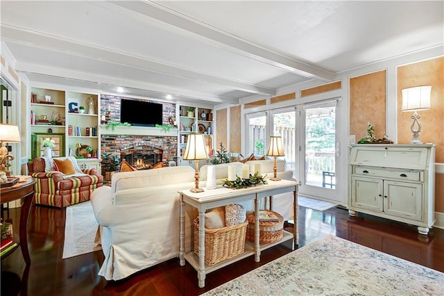 living area with beamed ceiling, dark wood-style flooring, a brick fireplace, and built in shelves