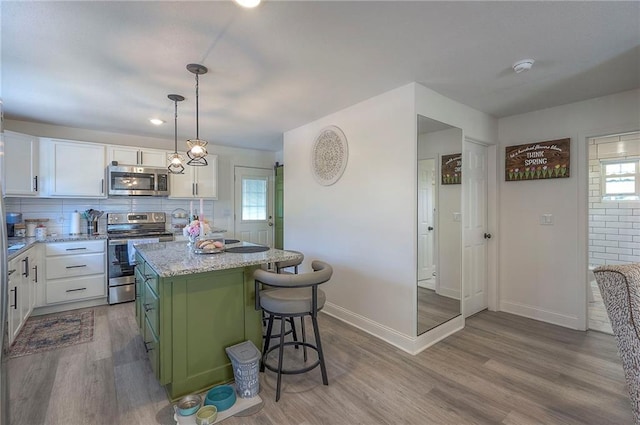 3118 Kimball Ave, Kansas City, KS 66104 - kitchen with appliances with stainless steel finishes, white cabinetry, wood finished floors, and a center island