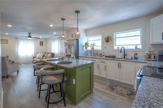 3118 Kimball Ave, Kansas City, KS 66104 - kitchen with stainless steel refrigerator with ice dispenser, a sink, a center island, white cabinets, and recessed lighting